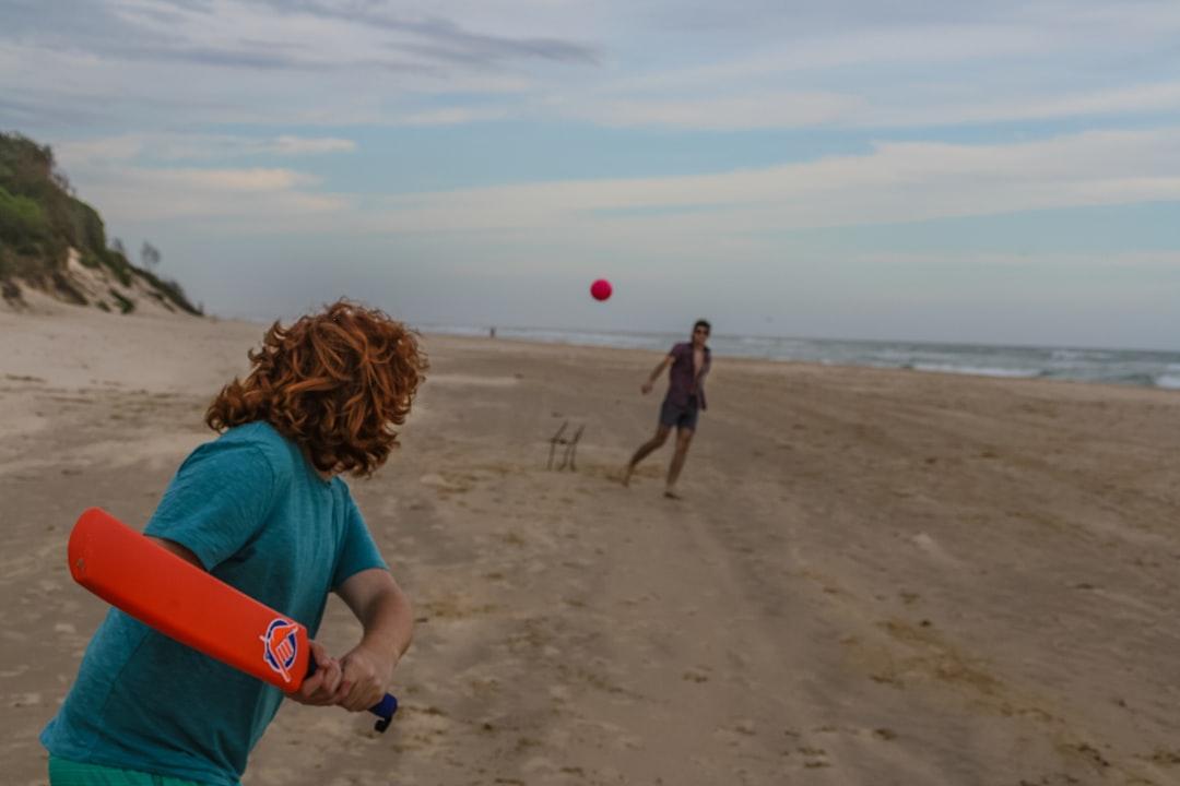 Person holding red cricket bat near seashore from Lochie Blanch on Unsplash