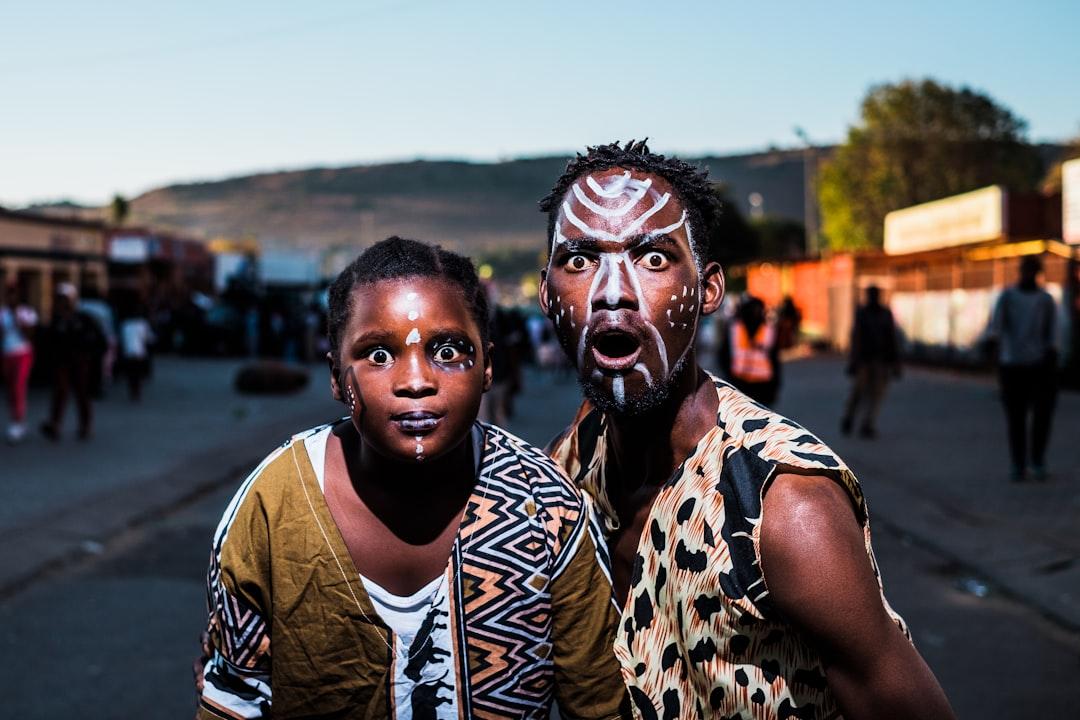 Two people with face paints taking photo in street from Mpumelelo Macu on Unsplash