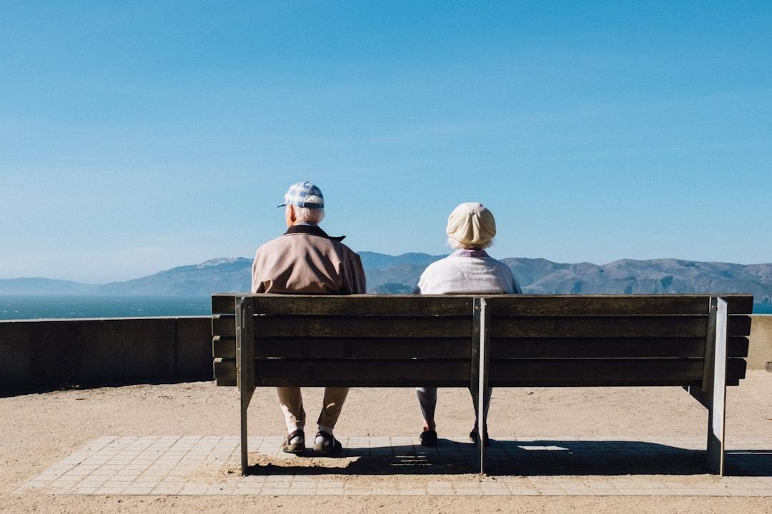 Man and woman sitting on bench facing sea from Matt Bennett on Unsplash