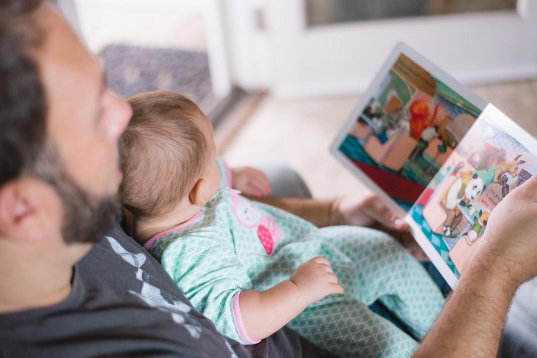 Person carrying baby while reading book from Picsea on Unsplash