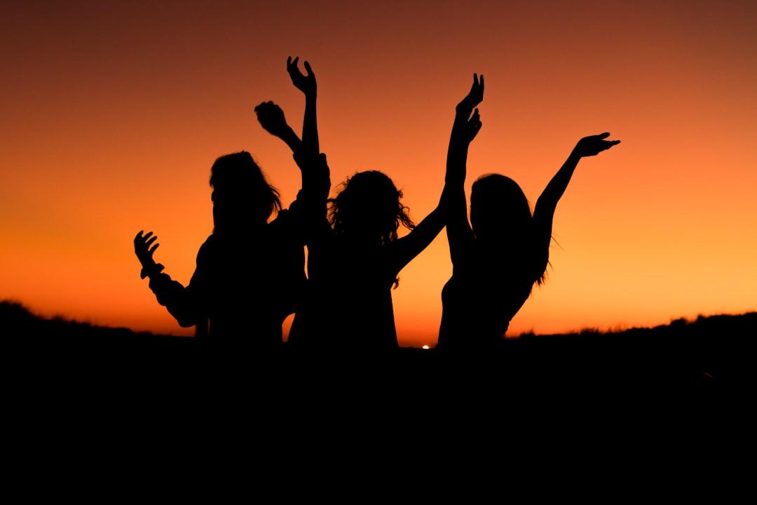 Silhouette of three woman with hands on the air while dancing during sunset from Levi Guzman on Unsplash