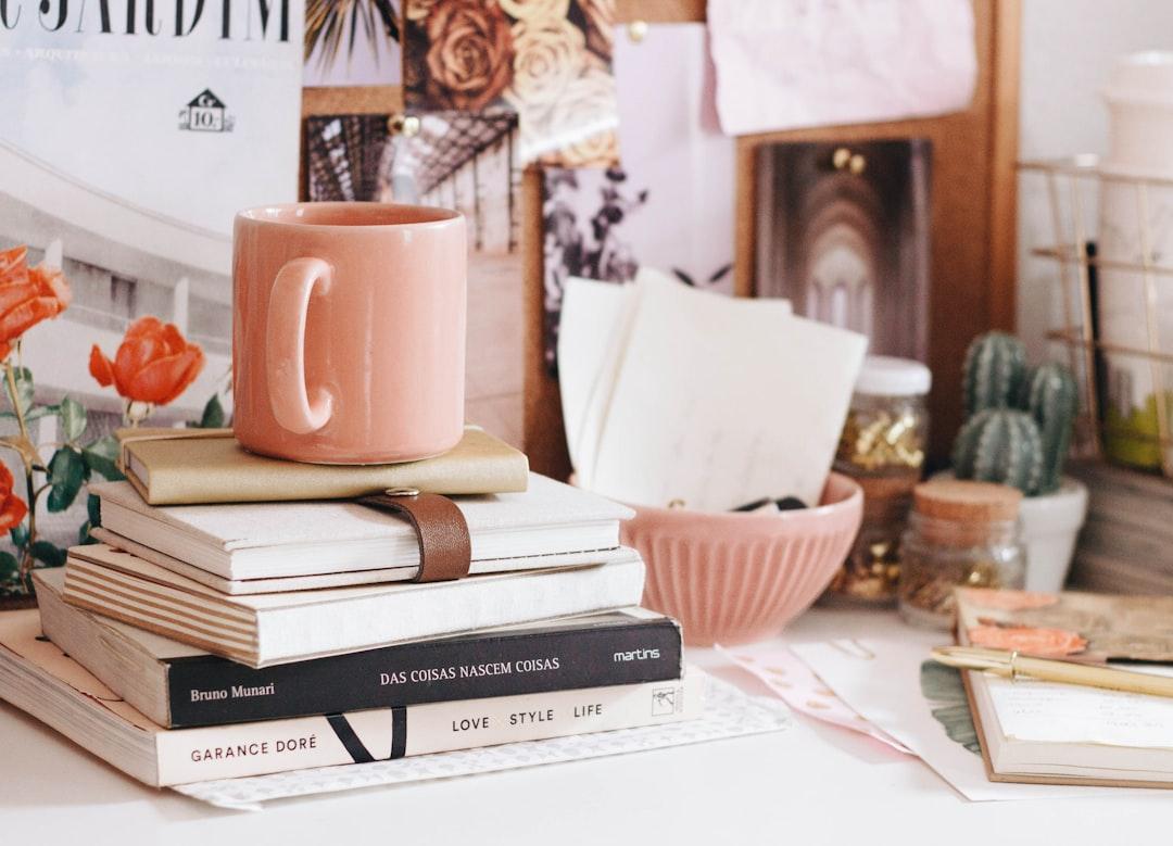 Brown ceramic coffee mug on book from Ella Jardim on Unsplash