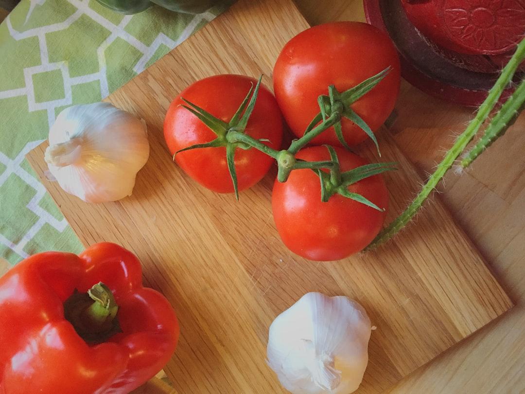 Three tomatoes beside garlic from Geo Darwin on Unsplash
