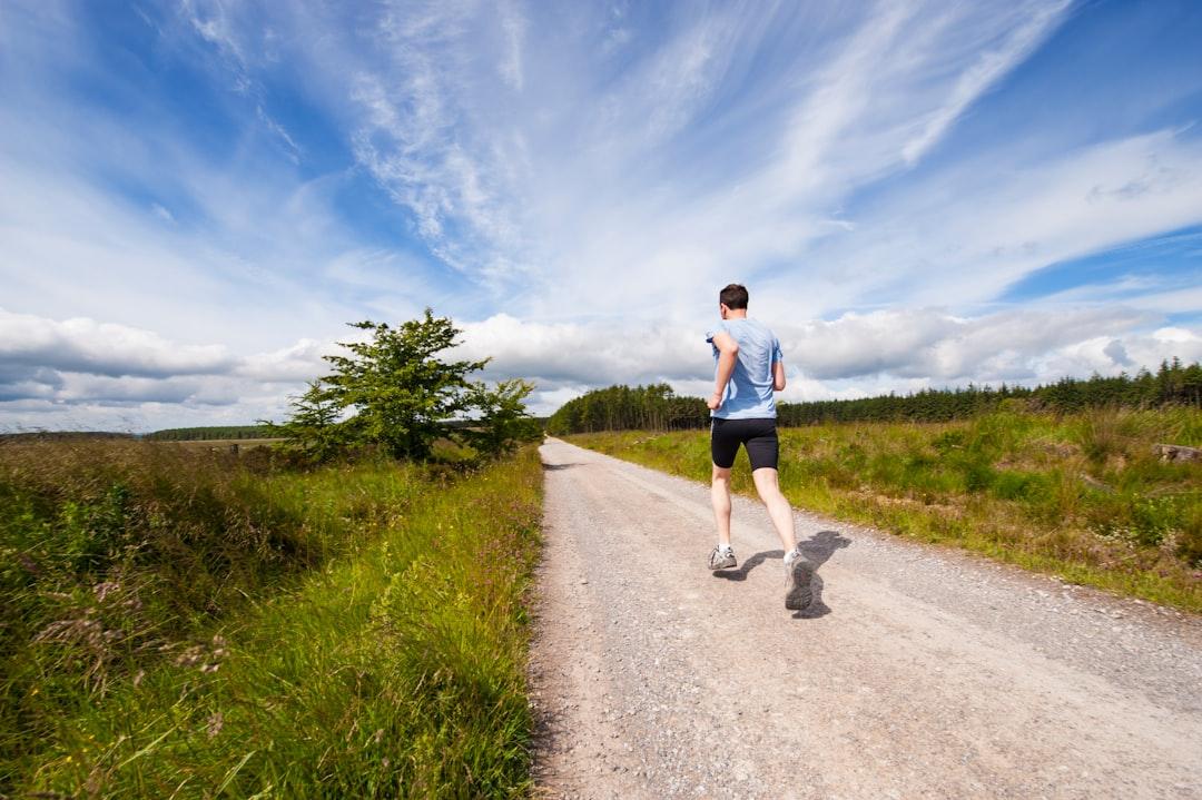 Man running on road near grass field from Jenny Hill on Unsplash