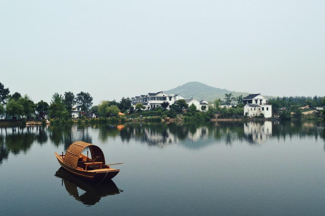 Brown wooden boat on body of water overlooking houses by the shore at daytime from Jennifer Chen on Unsplash