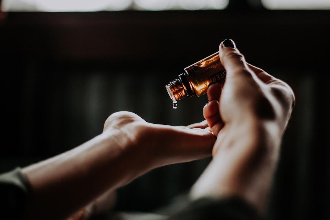 Person holding amber glass bottle from Christin Hume on Unsplash