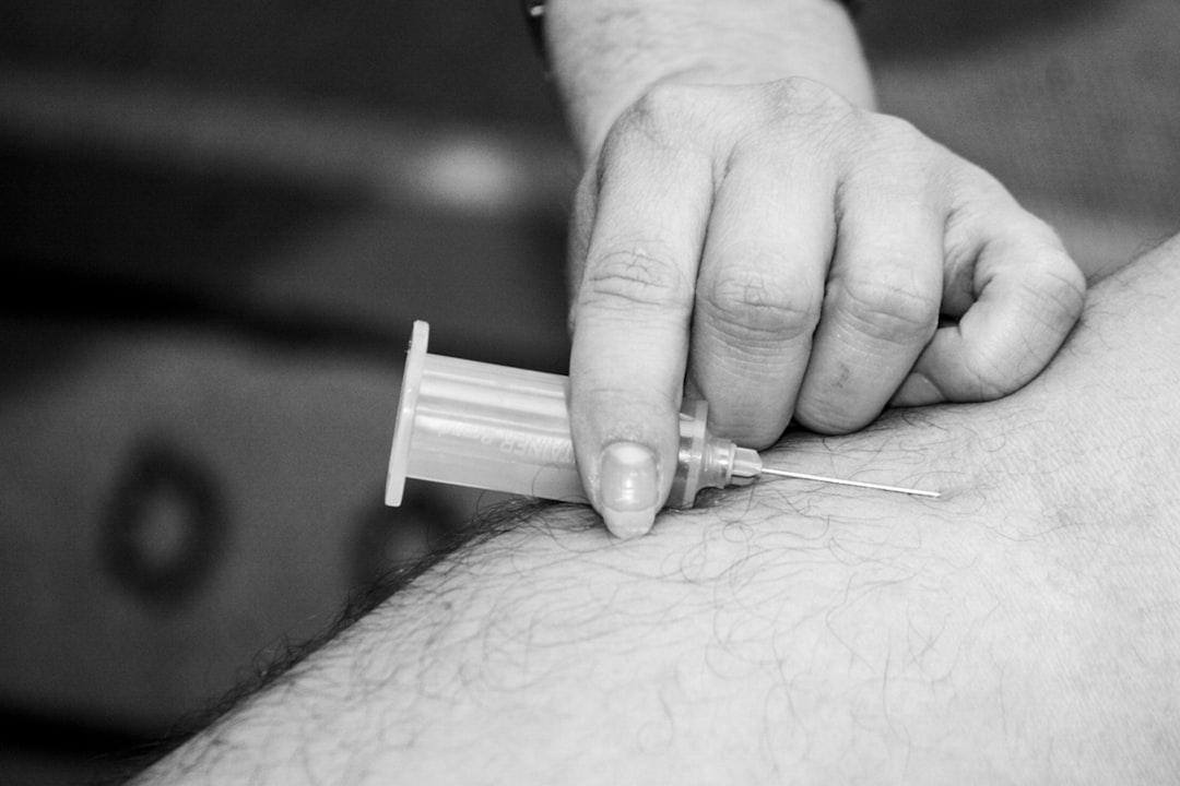 Grayscale photo of person holding syringe from Hush Naidoo Jade Photography on Unsplash Gần 14 bác sĩ nhãn khoa/triệu dân