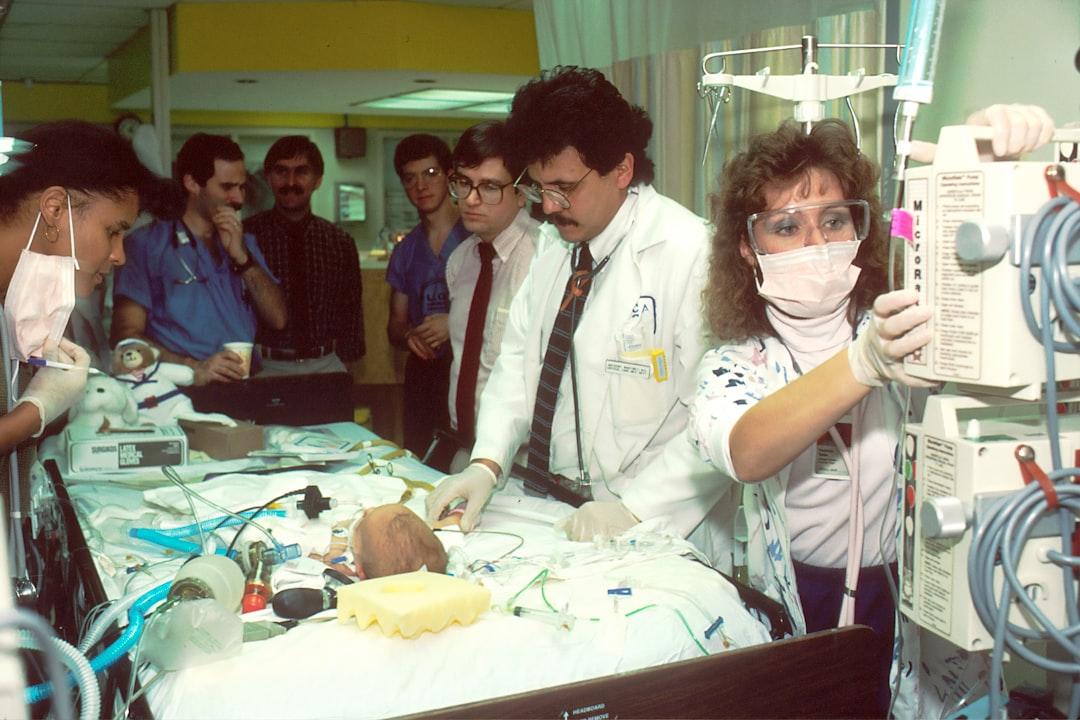 people beside baby lying on bed with medical apparatuses Đầu - Thóp