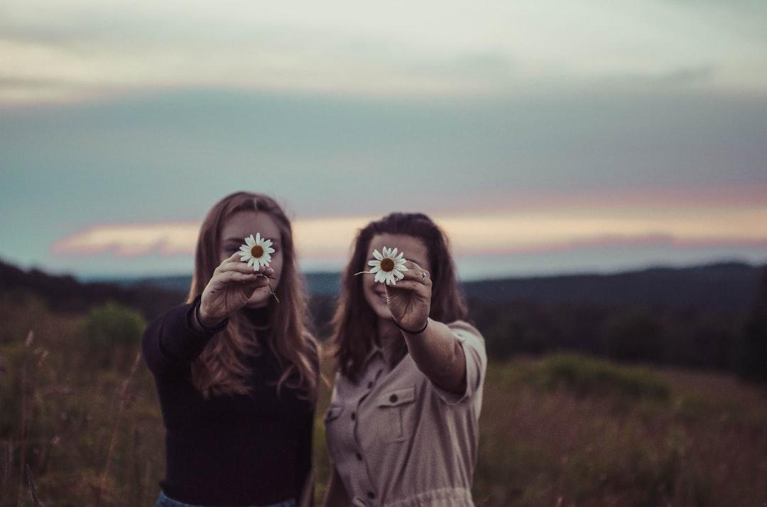 Two women holding flowers from Sam McNamara on Unsplash Dấu hiệu bệnh lậu ở nữ giới