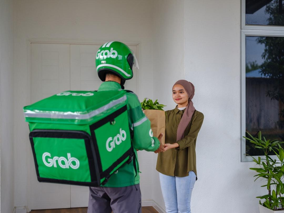 A man and a woman holding a giant green box from Grab on Unsplash Khi “áo mưa” thủng...