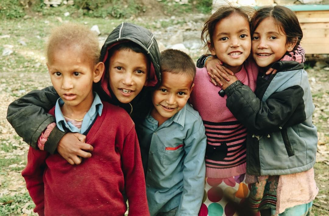 group of children standing on grass field during daytime Xương - Vẹo xương sống