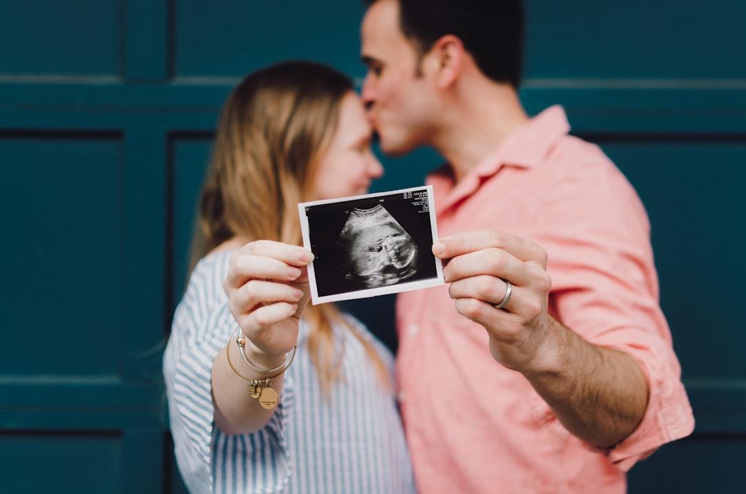 Man kissing woman's forehead white holding ultrasound photo from Kelly Sikkema on Unsplash Xương - Tật nứt đốt sống