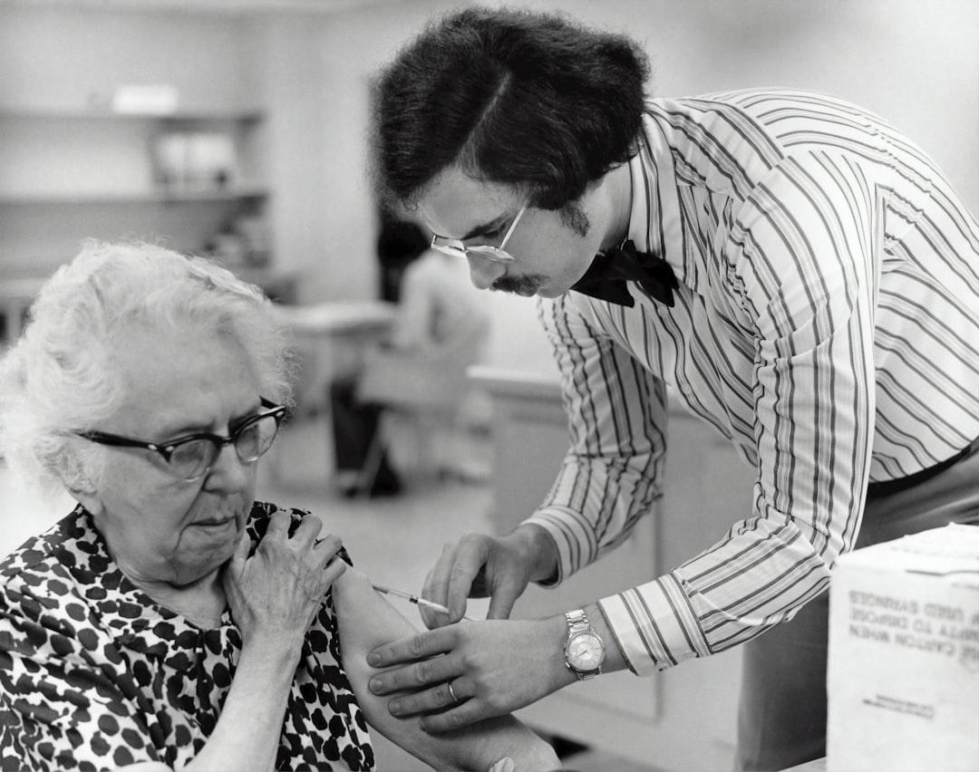 Grayscale photography of man holding syringe injecting on woman left arm from CDC on Unsplash Tiêm vaccine bạch hầu, ho gà, uốn ván chậm một tháng