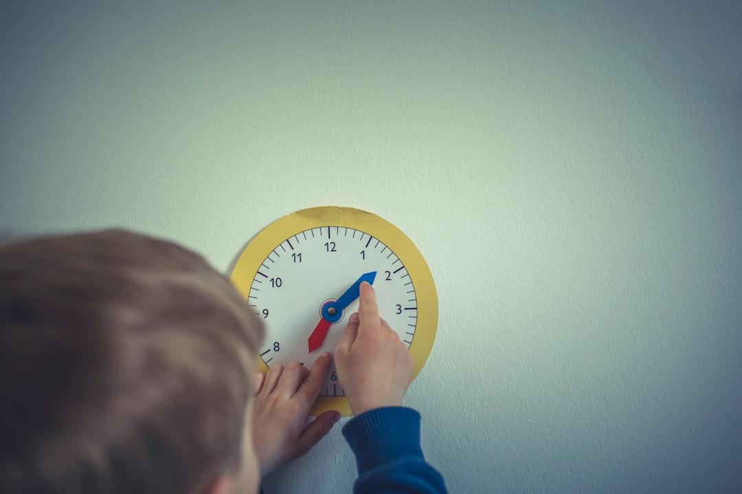person in blue long sleeve shirt holding white round analog wall clock Sinh dục, Bài tiết - Tật lỗ tiểu thấp