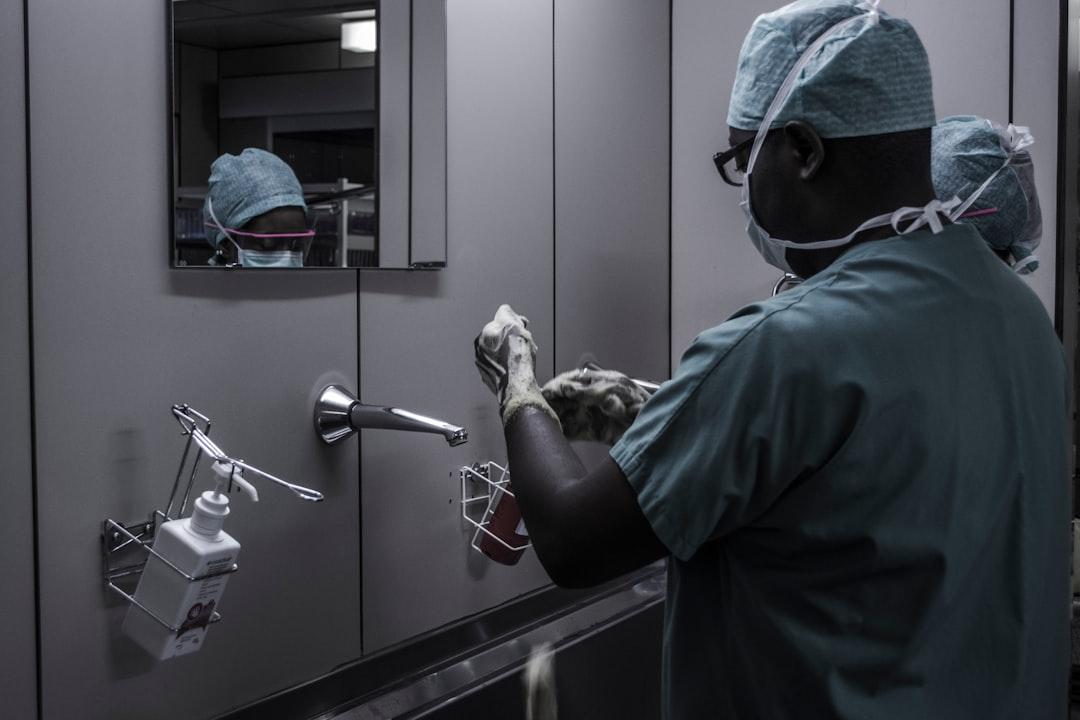 Man wearing surgical suit near mirror from Piron Guillaume on Unsplash Chết do bác sỹ không phát hiện chiếc đũa trong gan