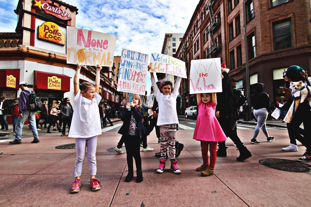 Four children raising up a banner at the middle of a busy street during day time from Nicole Adams on Unsplash Tỉnh táo với dấu hiệu của tai biến mạch máu não