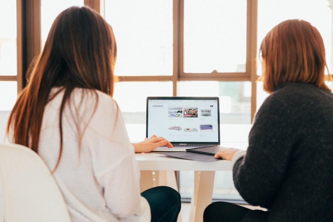 Two women talking while looking at laptop computer from KOBU Agency on Unsplash