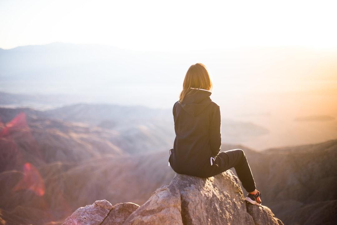 person sitting on top of gray rock overlooking mountain during daytime Phụ nữ tiền mãn kinh cần phải phối hợp như thế nào trong quá trình trị liệu