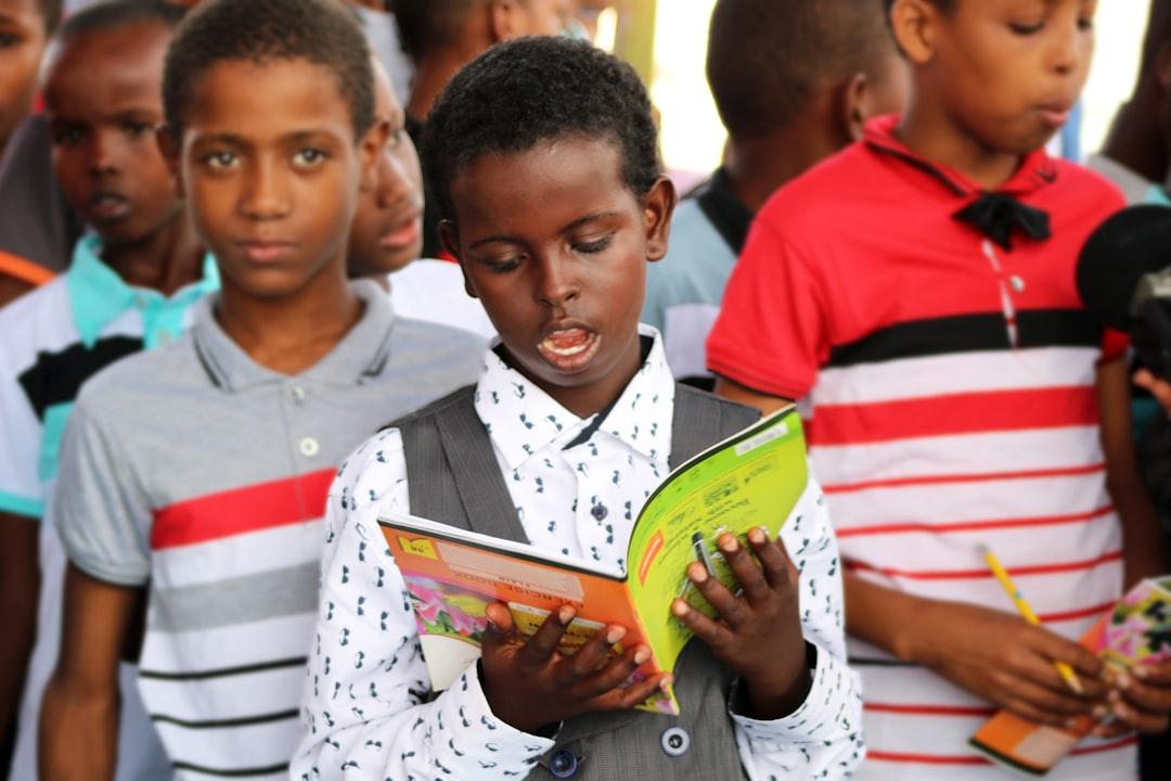 Man in red and white polo shirt holding yellow book from Ismail Salad Osman Hajji dirir on Unsplash Chương VIII. Khả năng nói của trẻ